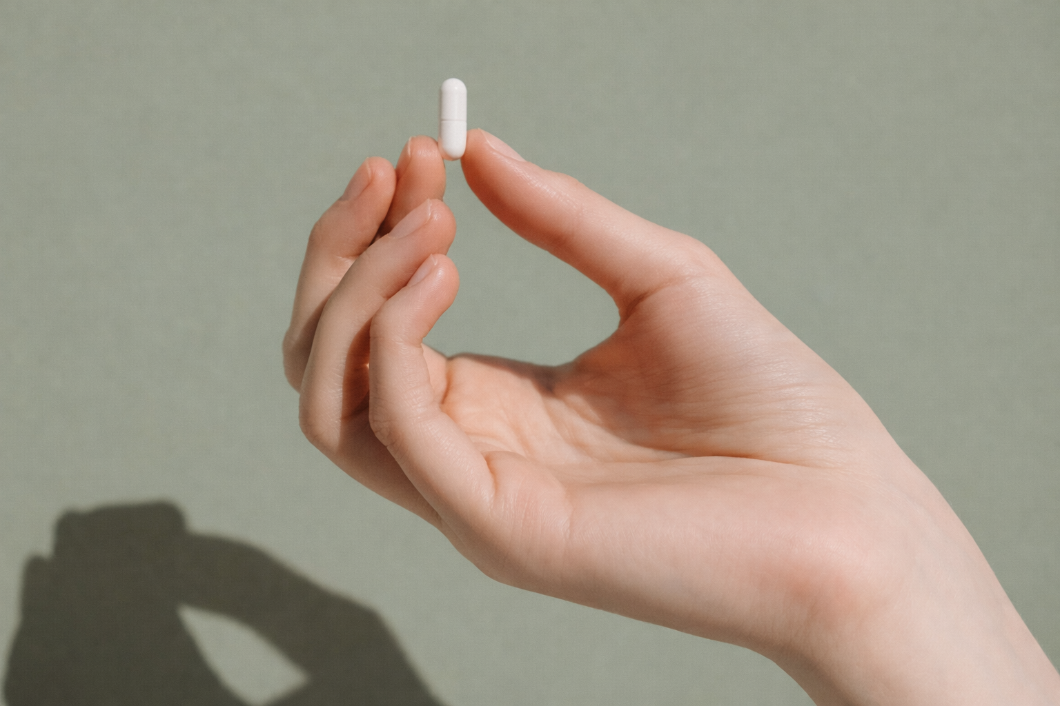 Hand holding a white Sanvee pill